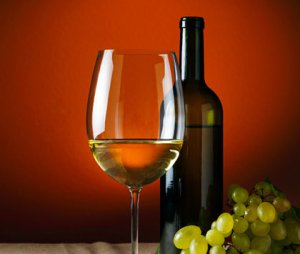 A picture of a wine glass, wine bottle and green grapes.